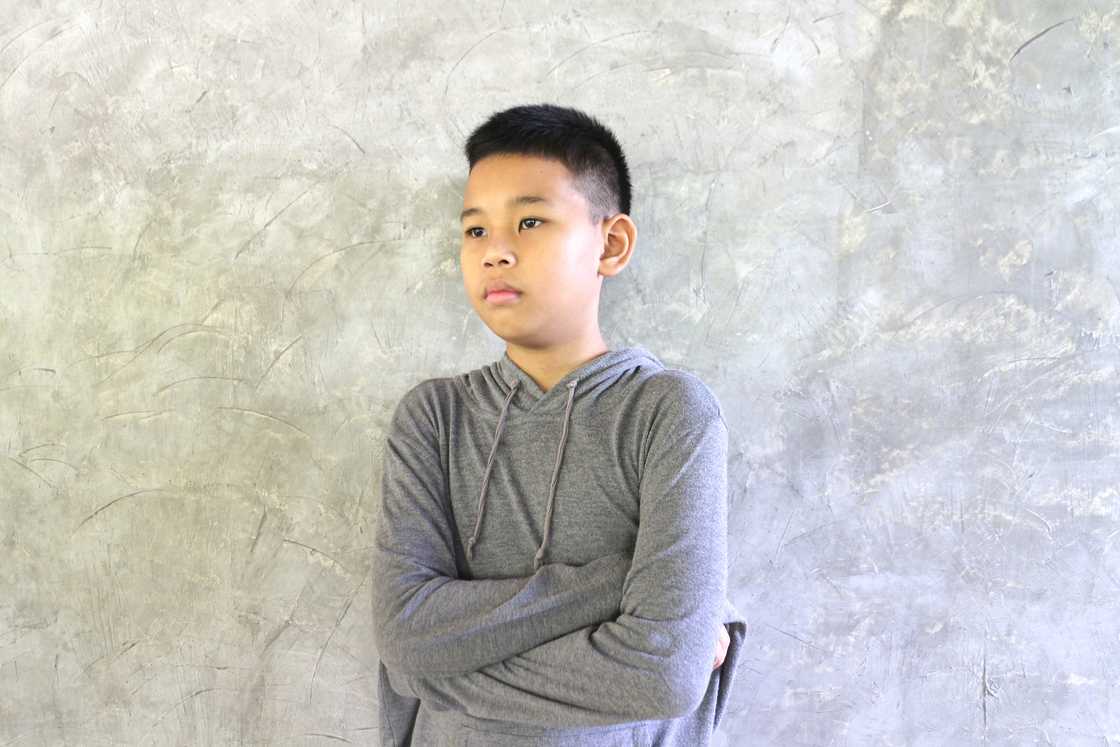 A boy feeling disgusted standing while folding his arms A boy feeling disgusted standing while folding his arms