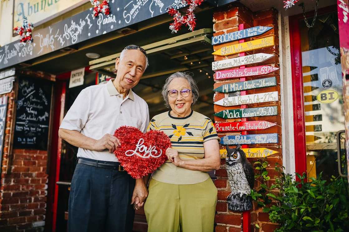 An elderly couple holding a red heart. An elderly couple holding a red heart.