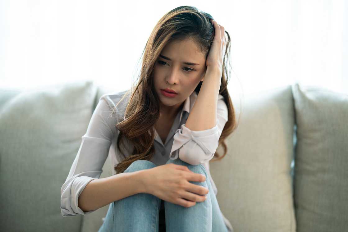 A young woman sitting on a couch with a distressed expression
