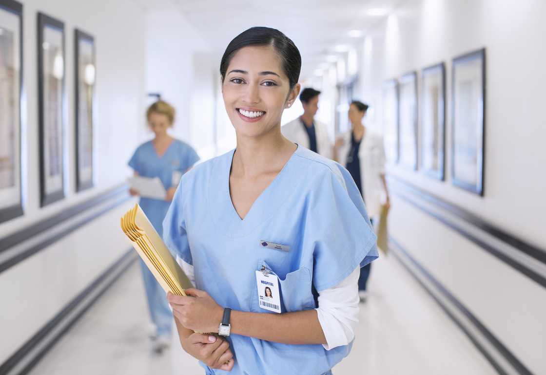 A nurse smilling while holding documents in a hospital A nurse smilling while holding documents in a hospital