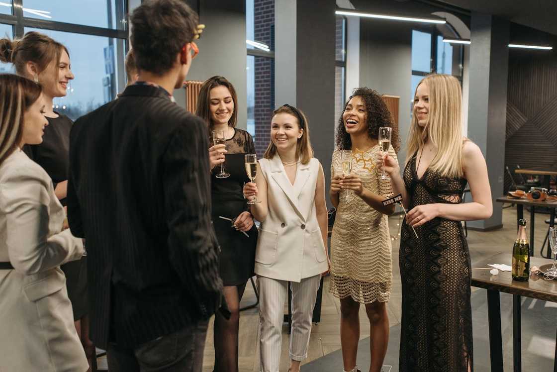 A group of well-dressed friends holding champagne glasses and chatting at an indoor party. A group of well-dressed friends holding champagne glasses and chatting at an indoor party.
