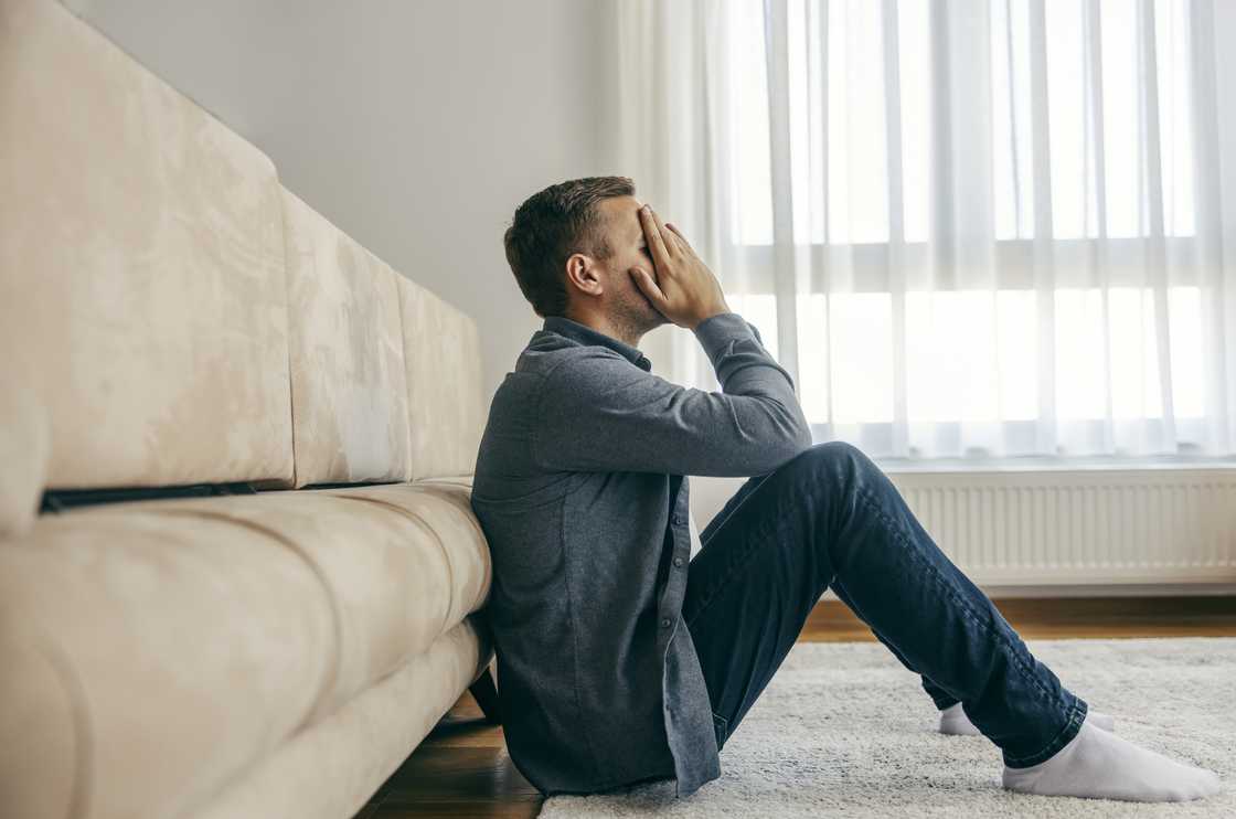 A regretful man is sitting on the floor A regretful man is sitting on the floor