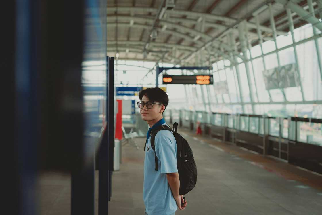A person in a modern terminal, looking with a backpack. A person in a modern terminal, looking with a backpack.