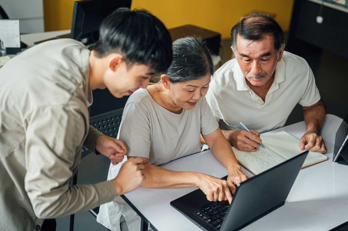 A young man instructing elederly people