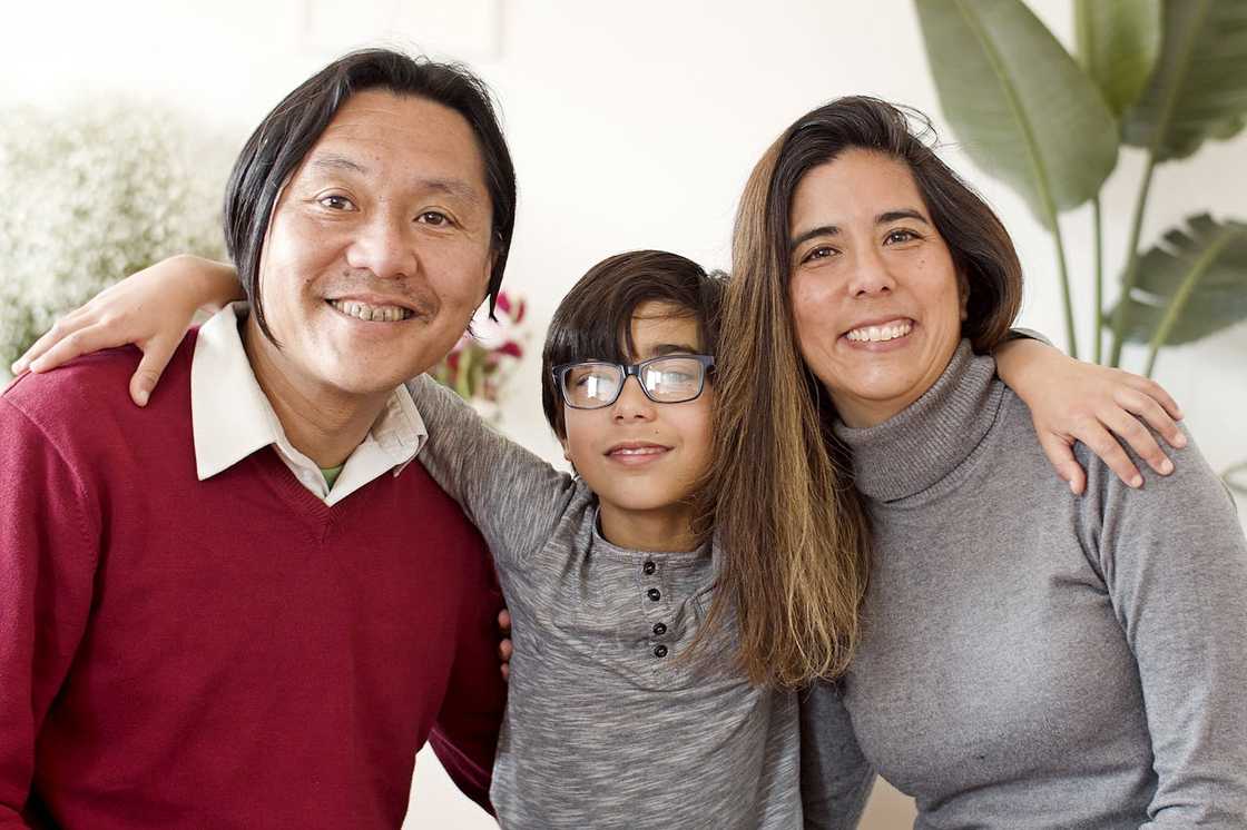 A smiling family poses with their arms around each other.