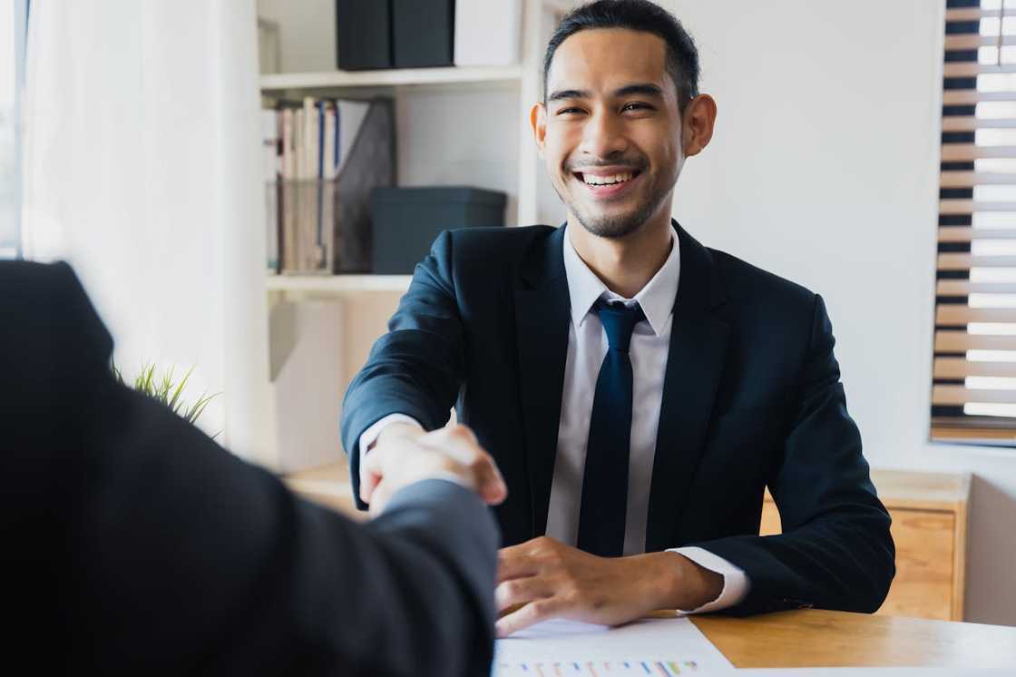 Smiling businessman in a suit shaking hands across a desk. Smiling businessman in a suit shaking hands across a desk.