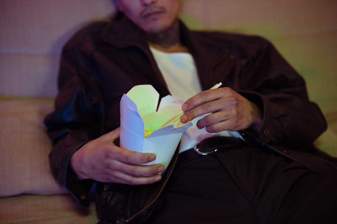Close-up of a man eating noodles from a box. Close-up of a man eating noodles from a box.