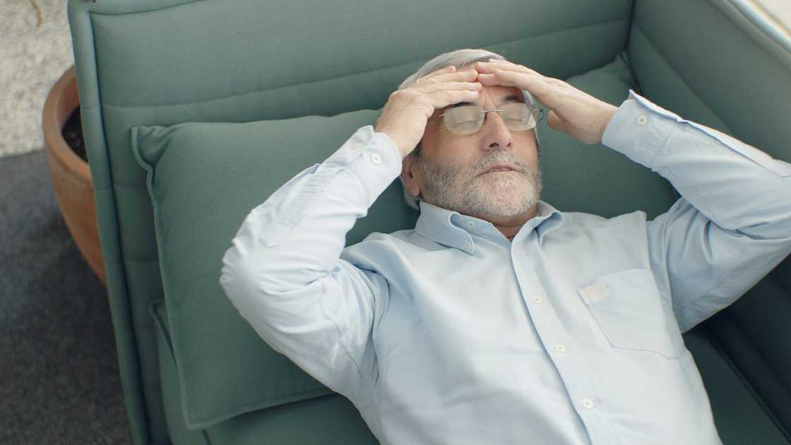 Older man lying back with hands on his head, looking stressed. Older man lying back with hands on his head, looking stressed.