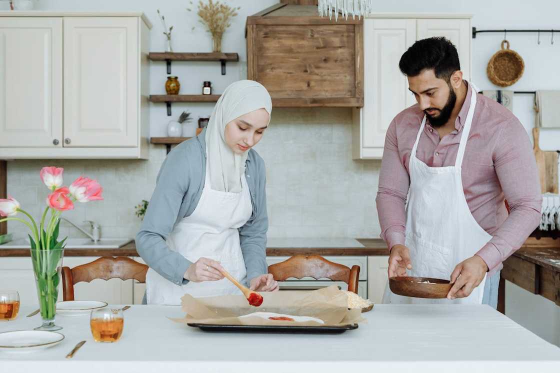 Two people in aprons making pizza in a modern kitchen. Two people in aprons making pizza in a modern kitchen.