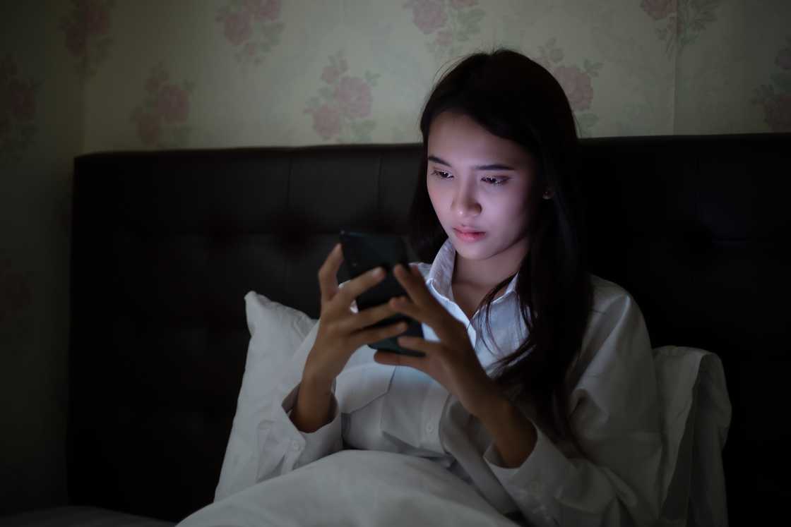 A woman reads an email on her phone at night