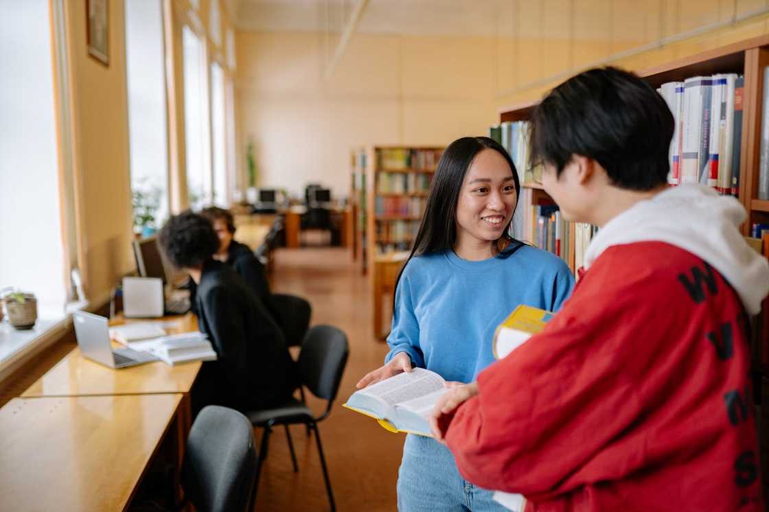A man and a woman talk inside a library. A man and a woman talk inside a library.