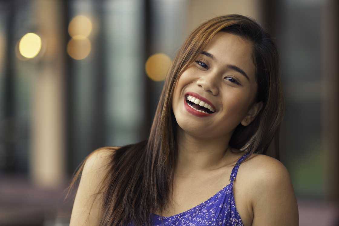 A young woman laughing outdoors.