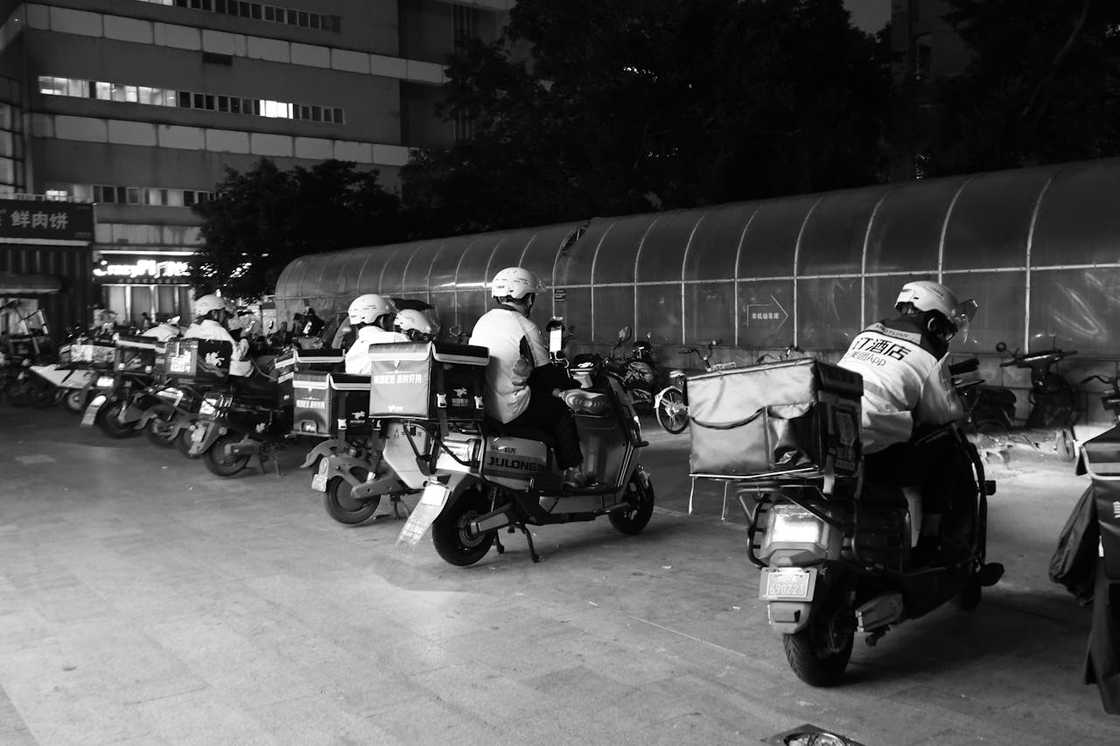 Row of delivery riders on scooters waiting at night. Row of delivery riders on scooters waiting at night.