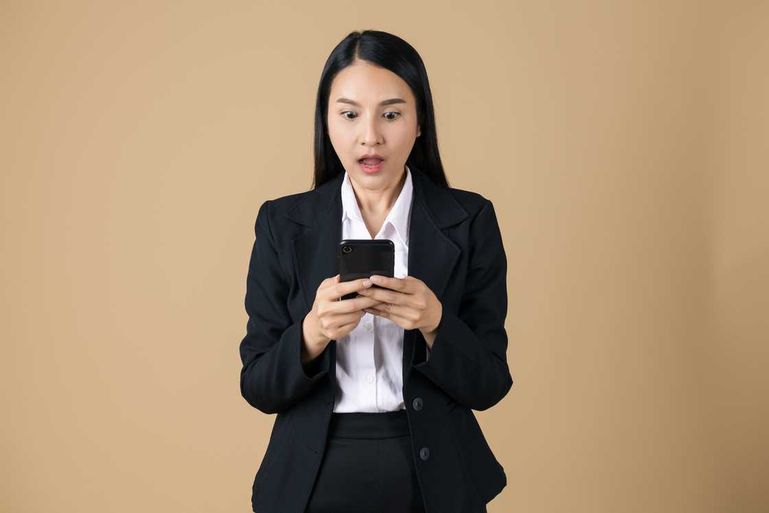 A shocked woman reads text from her phone