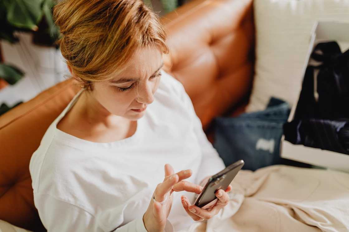 Woman seated on a sofa, checking her phone quietly.