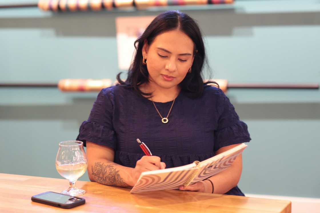 A person in a purple top writes in a notebook.