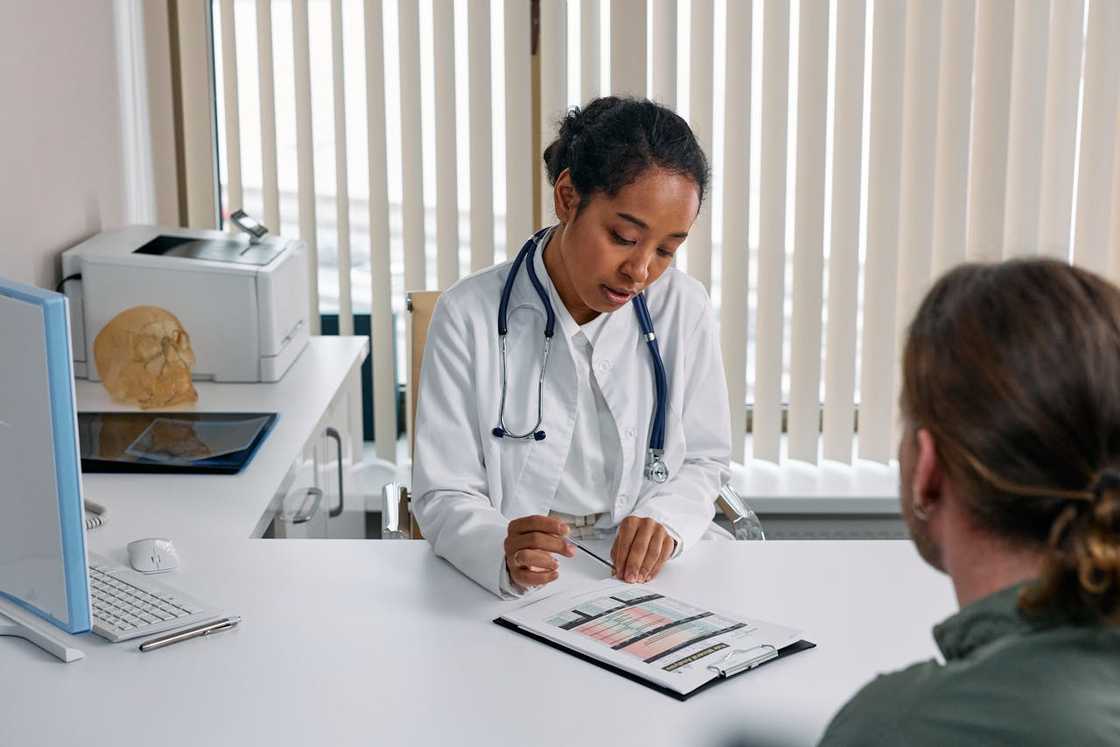 A man speaks anxiously with nurses at a station. A man speaks anxiously with nurses at a station.