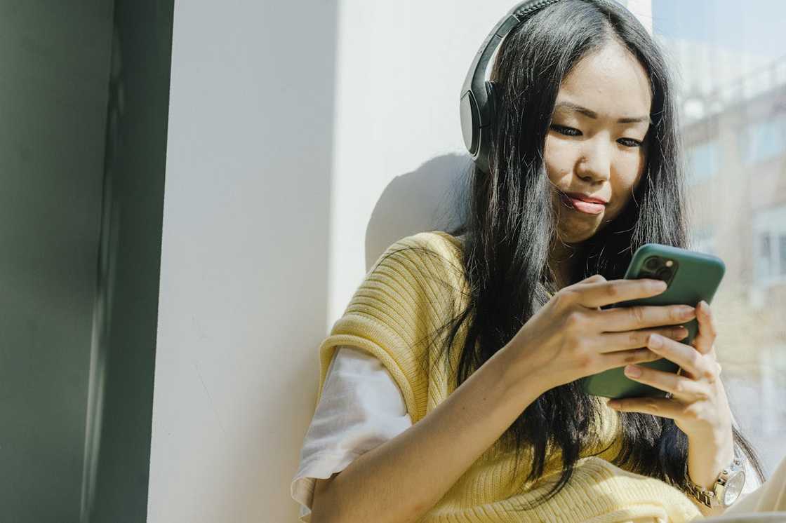 A young woman scrolls through her smartphone outdoors. A young woman scrolls through her smartphone outdoors.