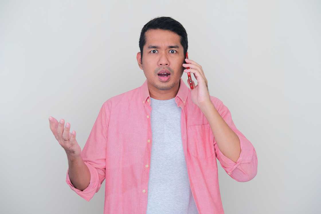 A shocked man answering a phone call