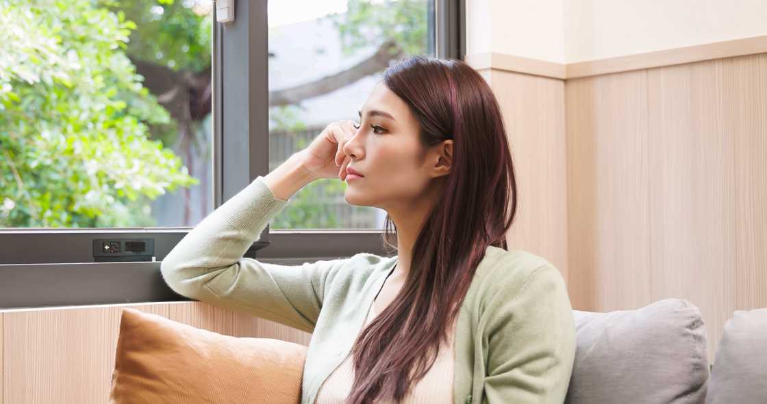 A woman feel looking outside a window and thinking