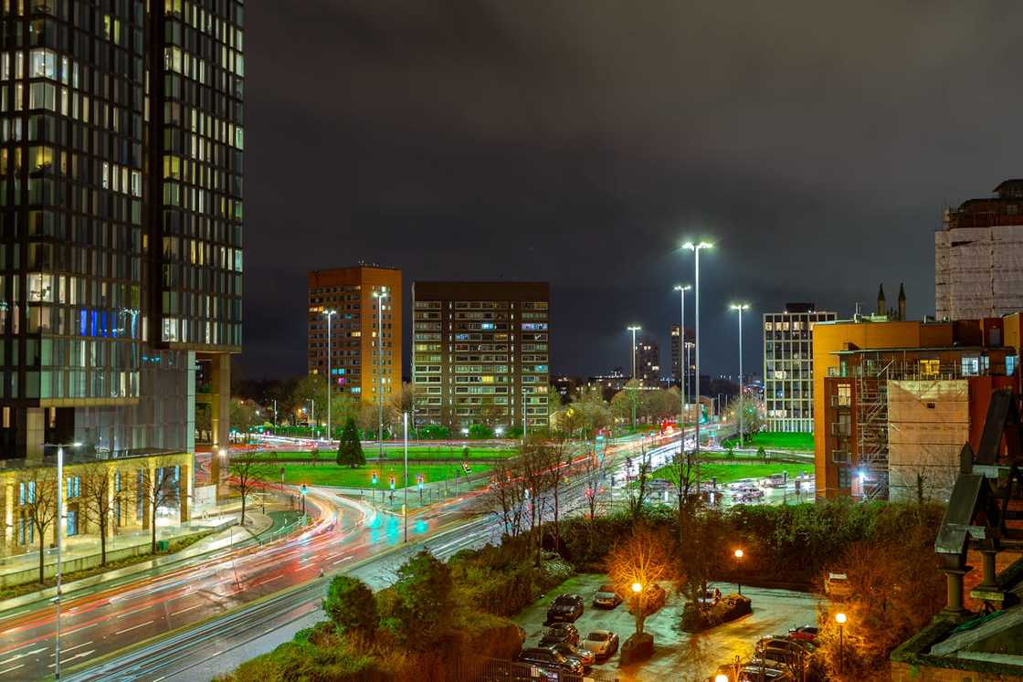 A night view of Manchester city centre with illuminated buildings and busy roads.