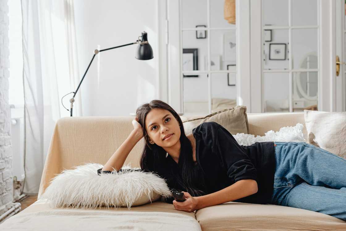 A young woman watching TV and holding a remote control