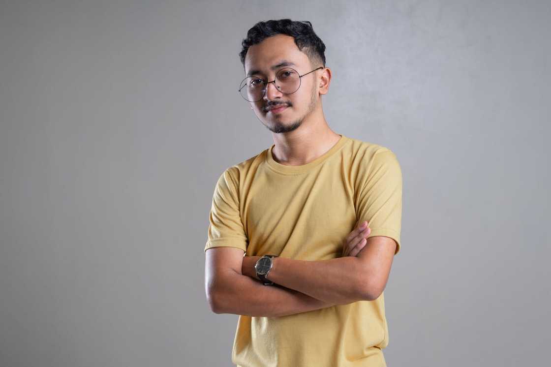 A man with arms crossed against a plain grey background. A man with arms crossed against a plain grey background.