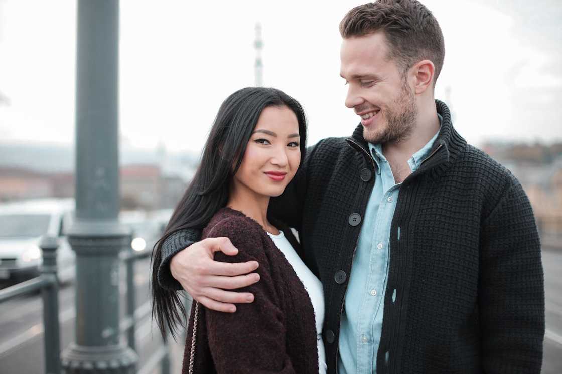 A smiling couple standing close together outdoors.