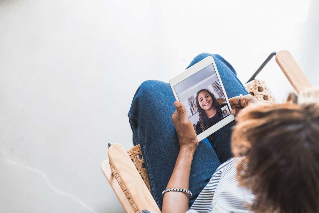 A young woman on a video call with her mum on a tablet.