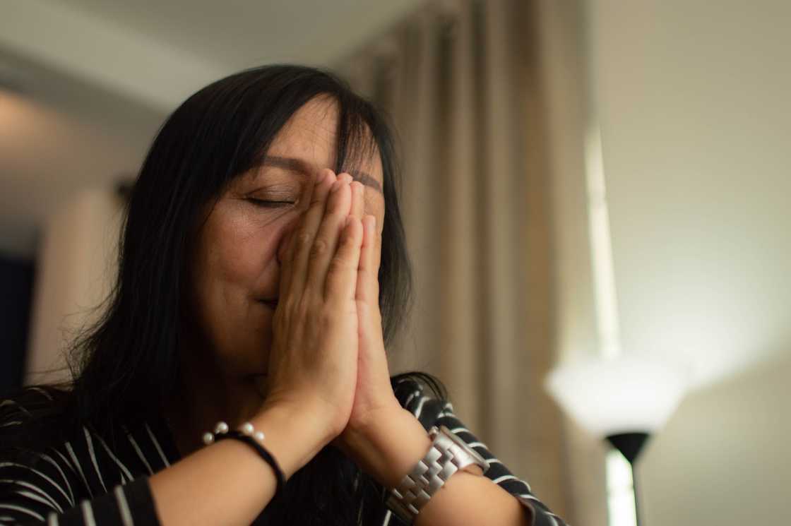 A tense woman sobbing and praying in a house