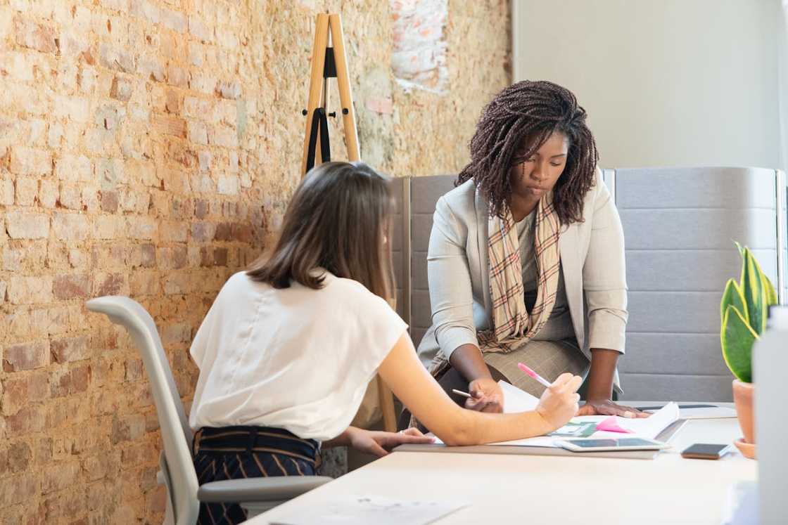 Two women reviewing documents together at the office. Two women reviewing documents together at the office.
