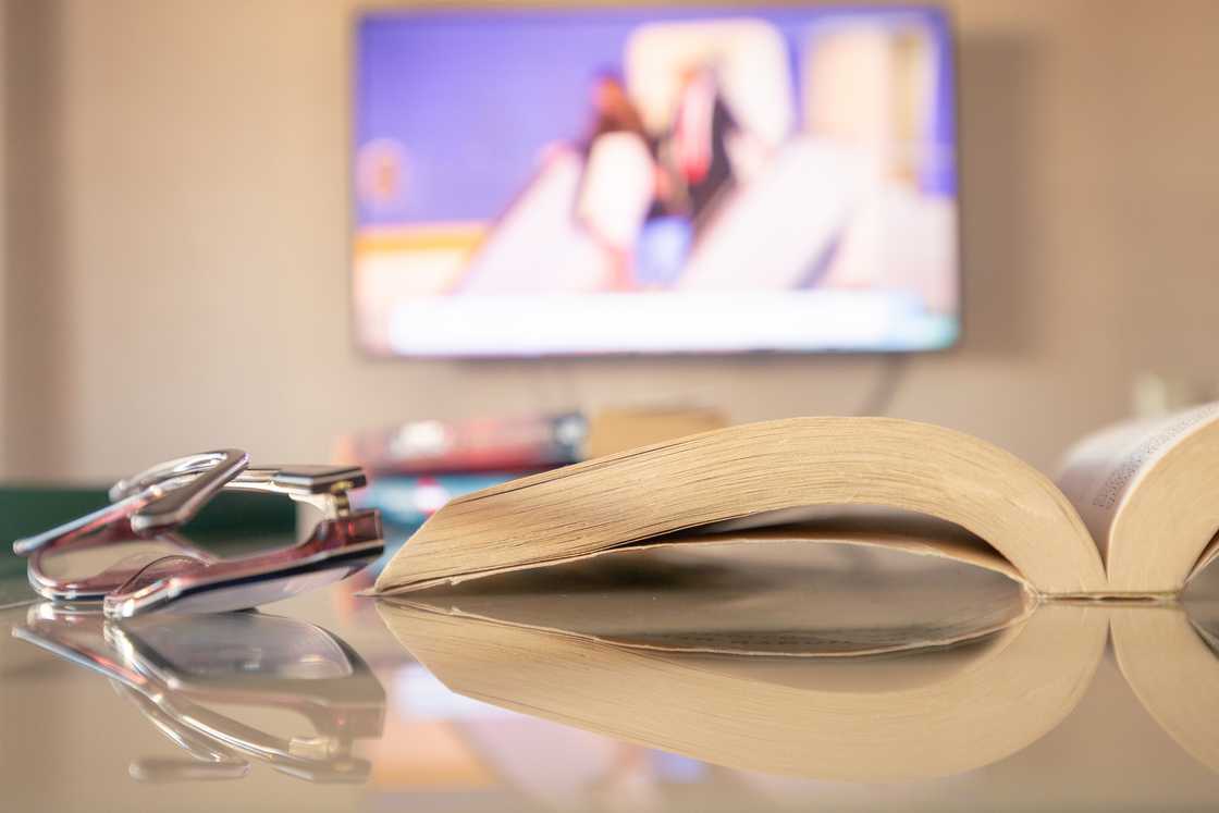 A cosy living room with with a TV and an open novel.