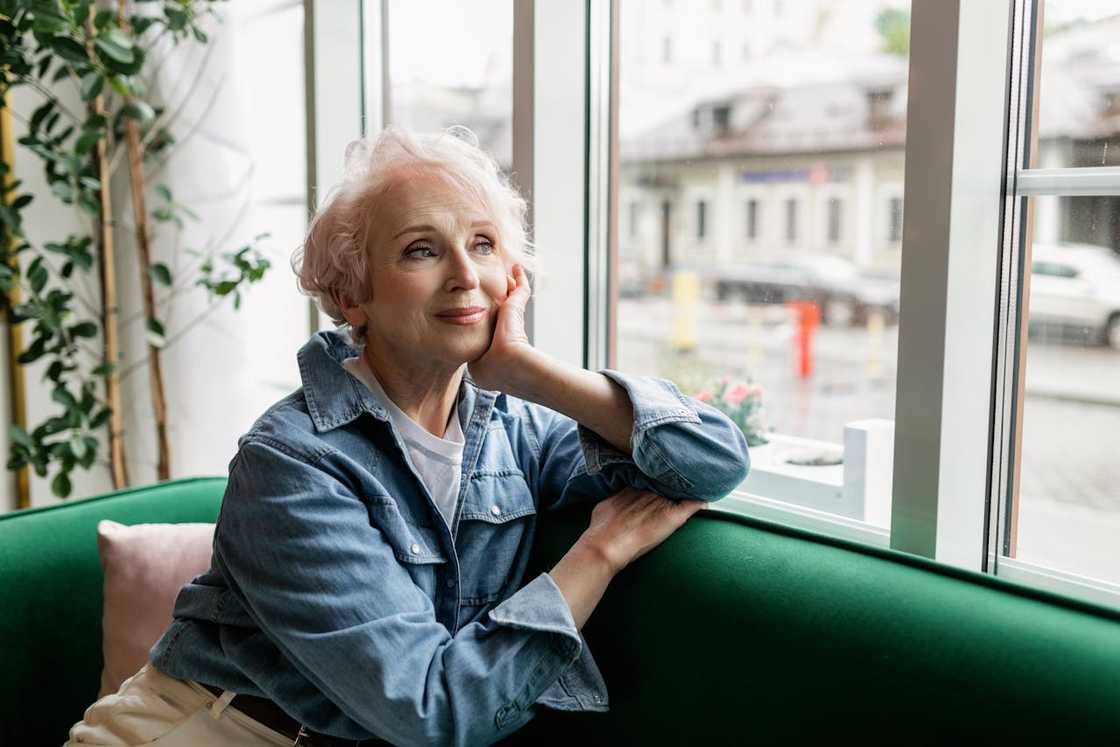 An older woman gazing thoughtfully through the café window. An older woman gazing thoughtfully through the café window.
