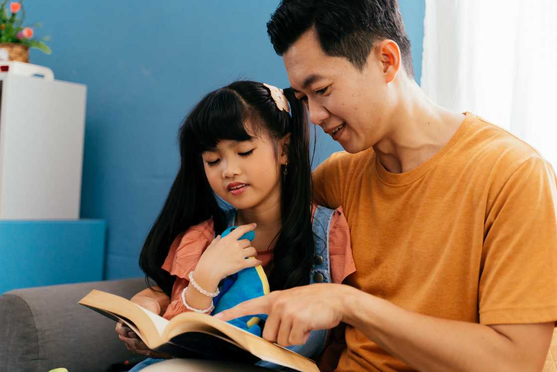 Asian dad reading storybook to daughter Asian dad reading storybook to daughter