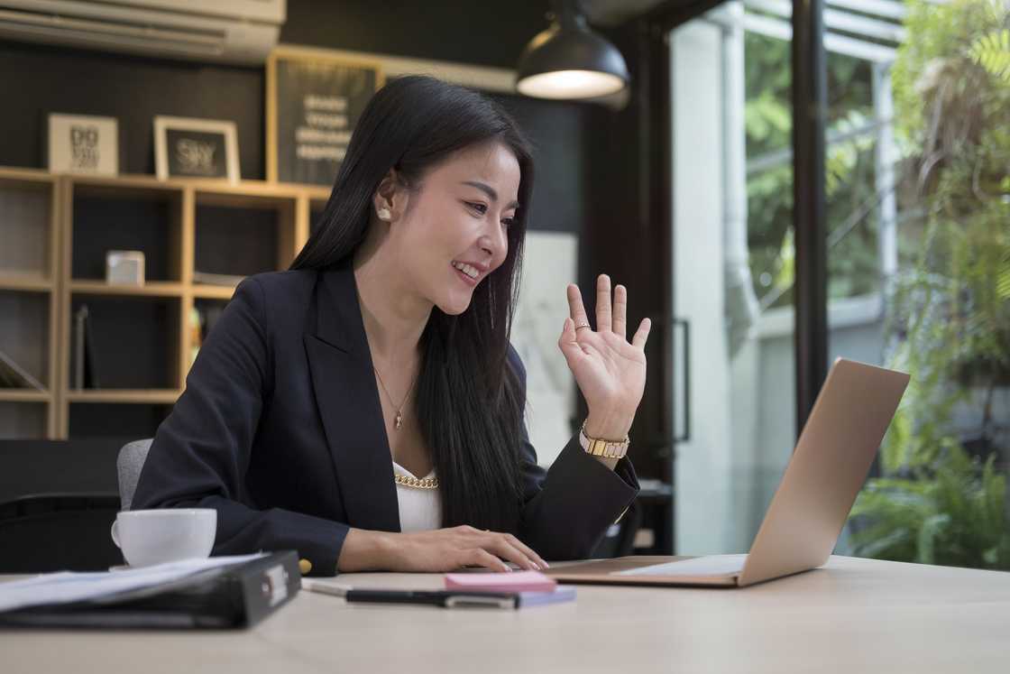 A lady waves during a video call A lady waves during a video call
