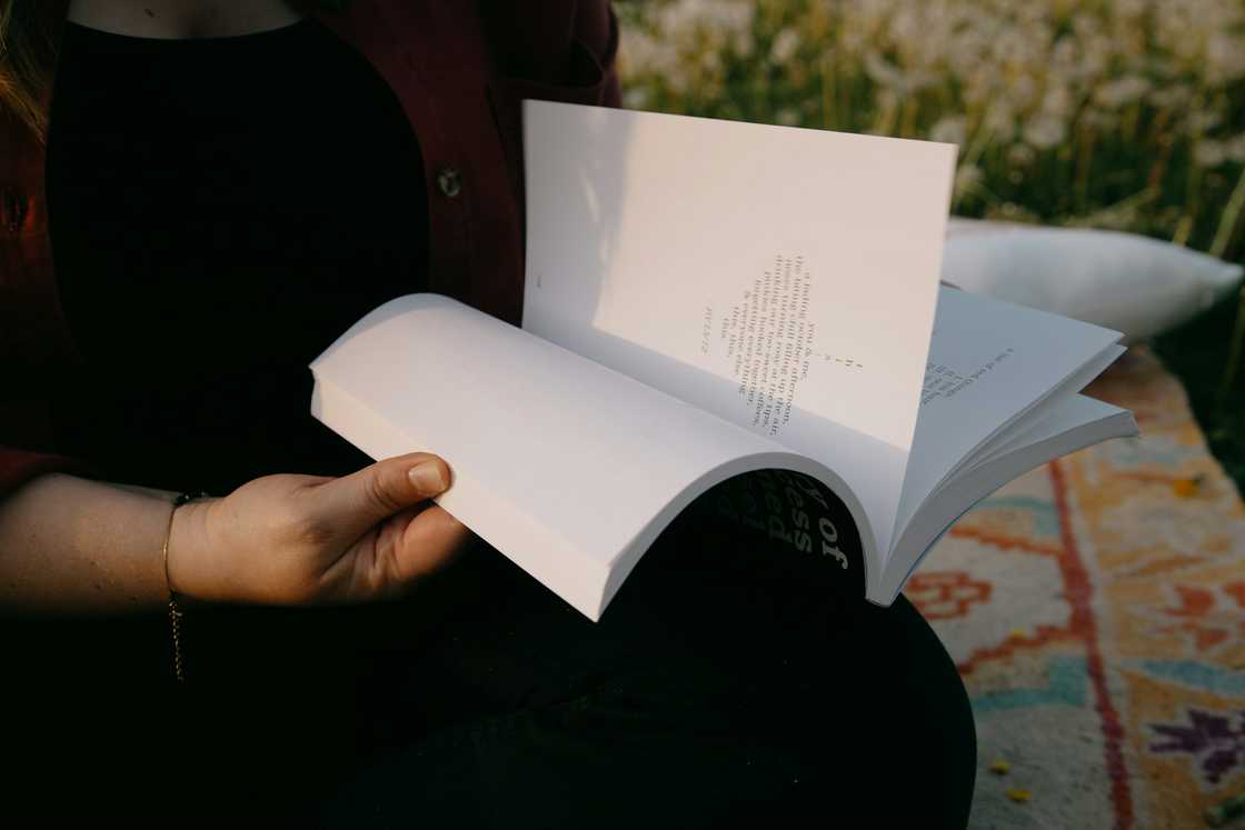 A person in a red sweater holds an open book.
