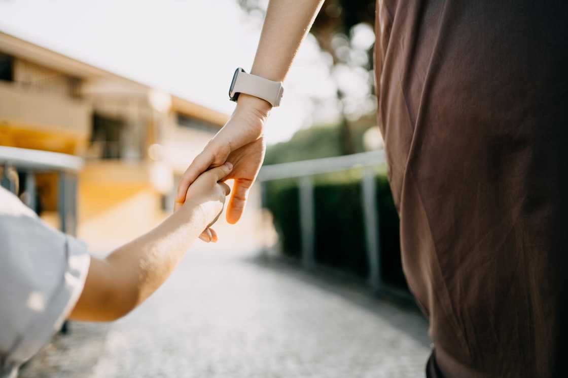 A girl and an adult lady are holding hands