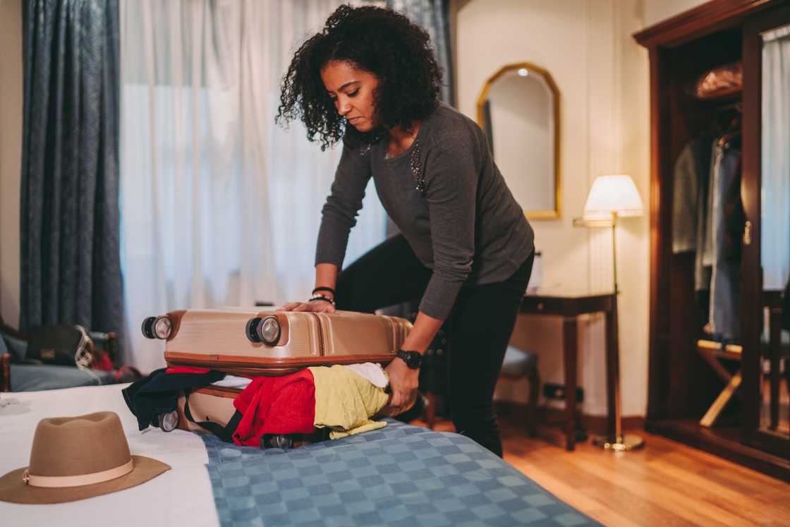 A woman is packing clothes into a suitcase.