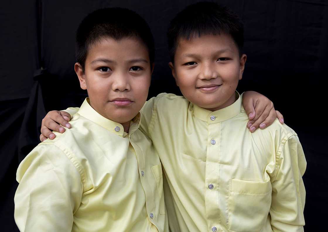 Two schoolboys stand with arms across each other Two schoolboys stand with arms across each other