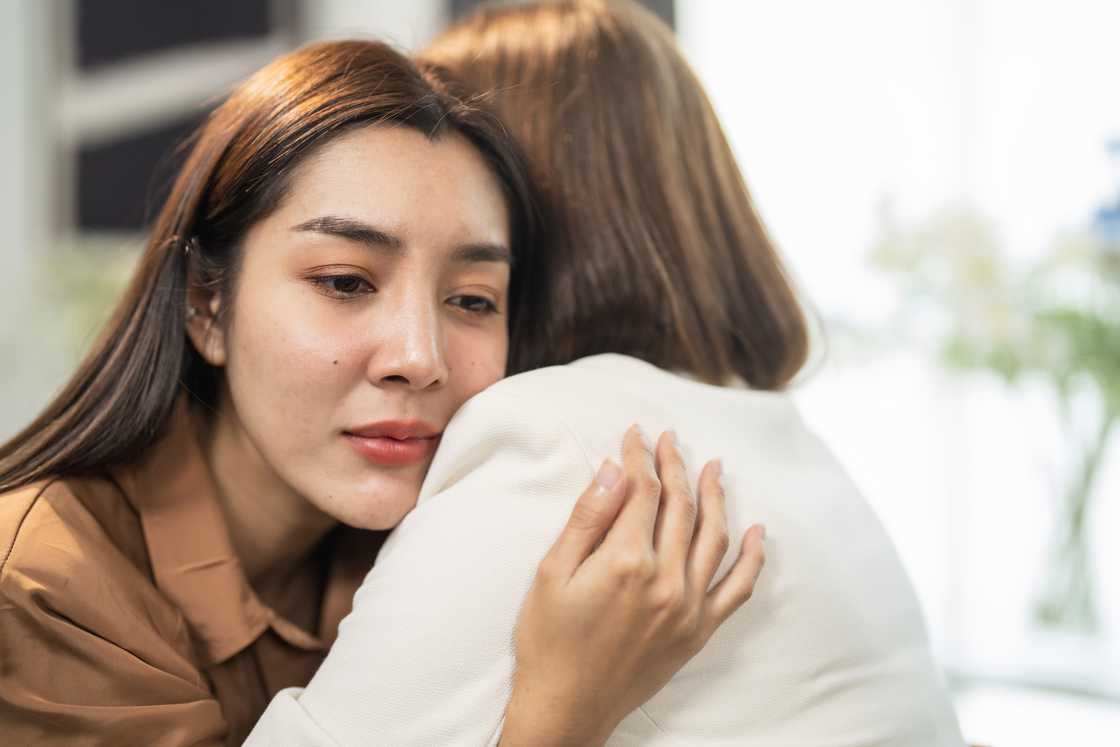 Two women express emotional support through a heartfelt hug