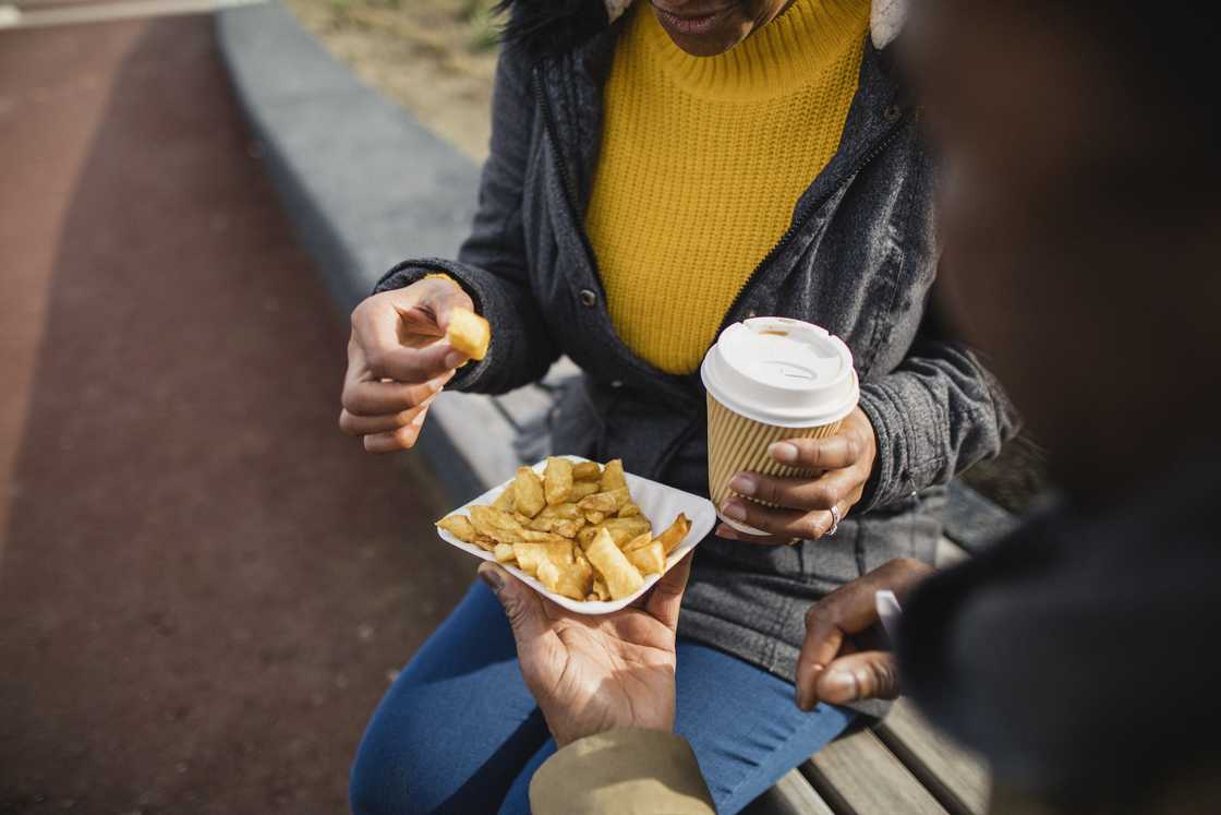 A lady sharing food with a man in the streets A lady sharing food with a man in the streets