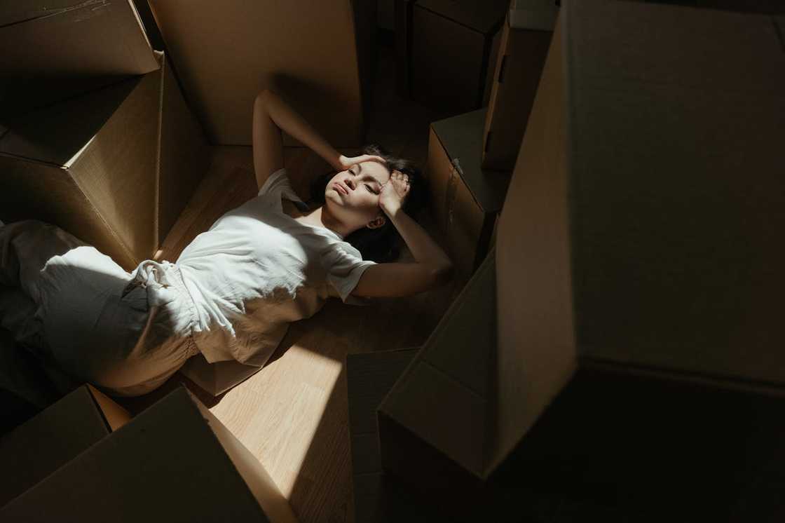 A person lies on a wooden floor in sunlight.