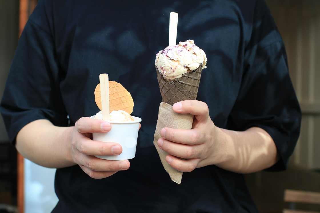 An ice cream vendor holds two ice creams An ice cream vendor holds two ice creams