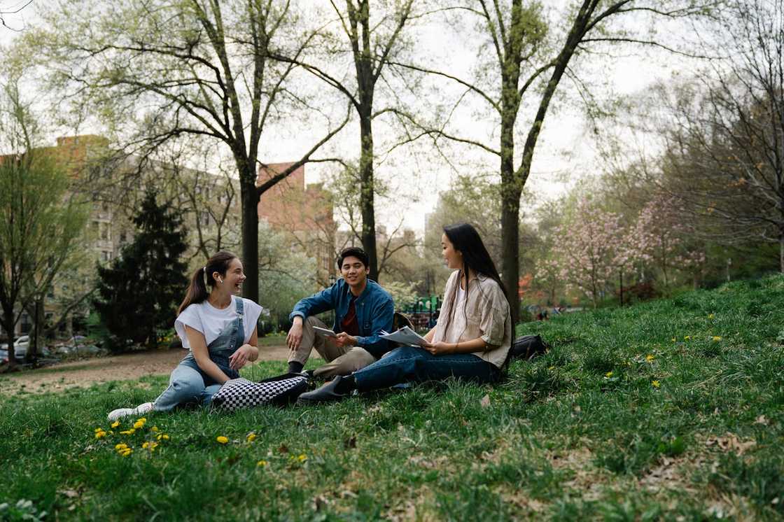 Four friends laughing on campus lawns.