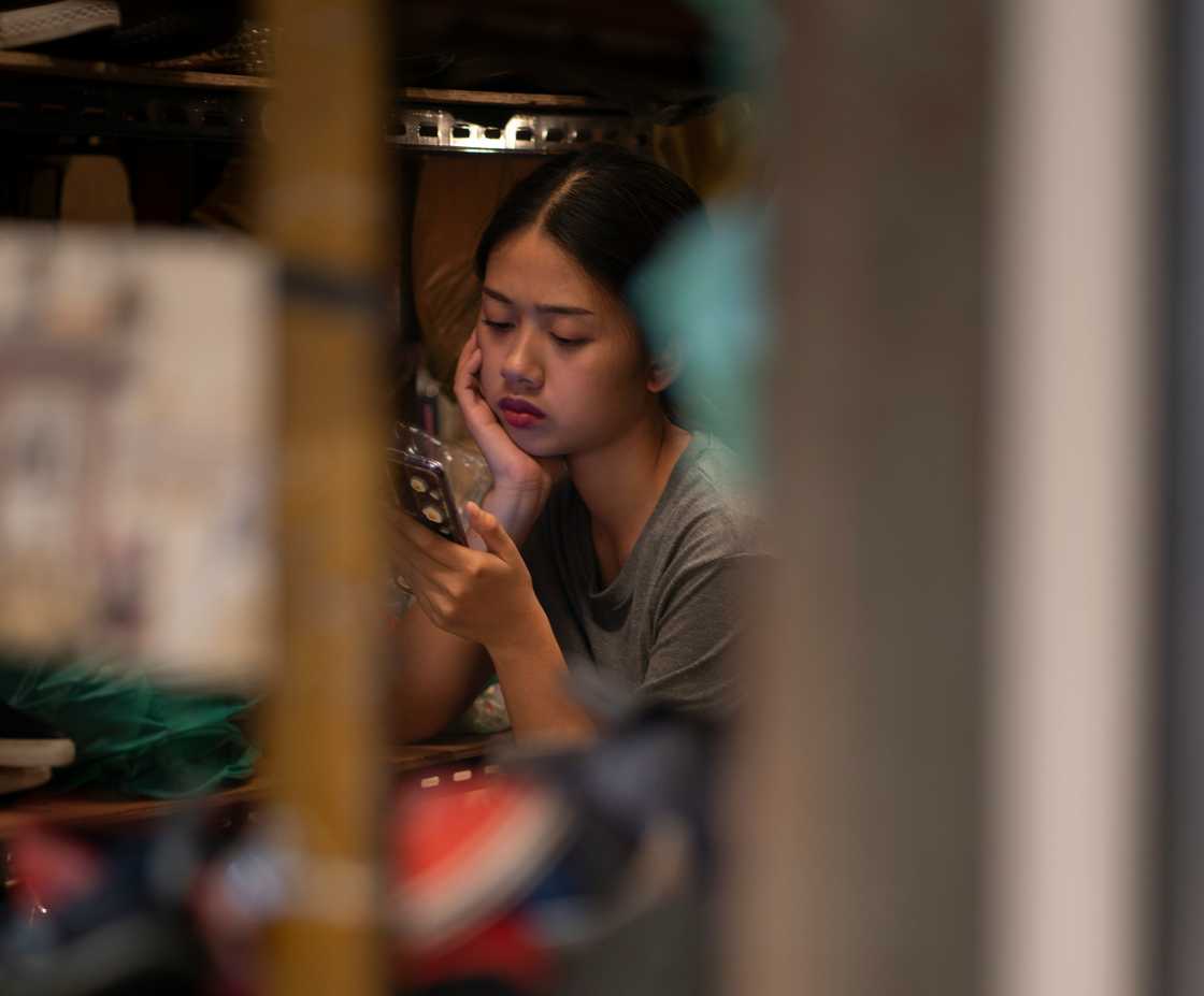 A shocked young woman looking at a mobile phone screen