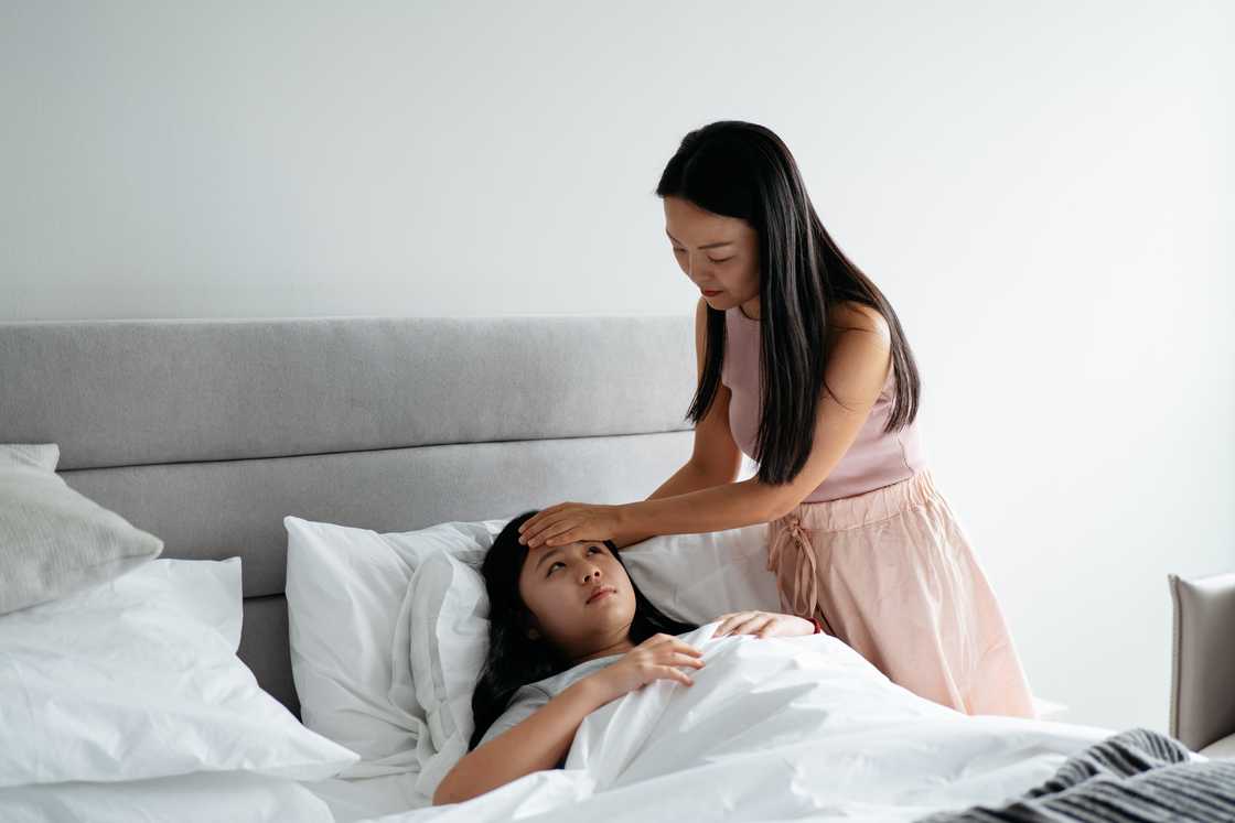 Asian woman checking a child's temperature Asian woman checking a child's temperature