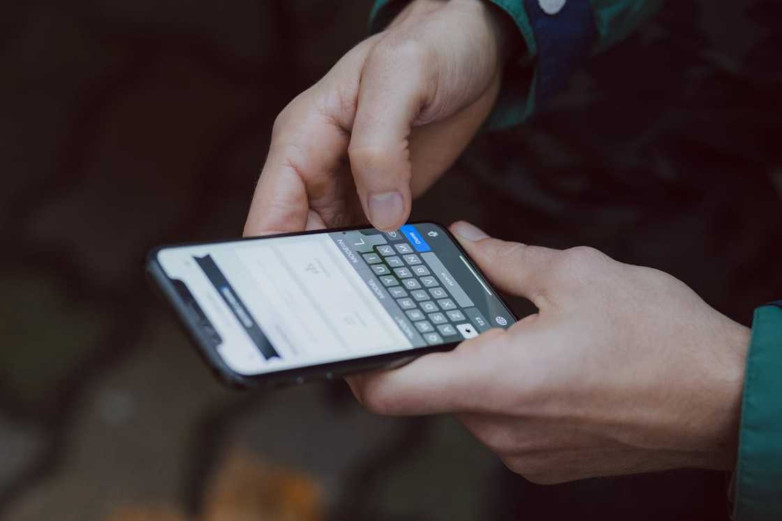 Close-up of hands typing a message on a smartphone screen.