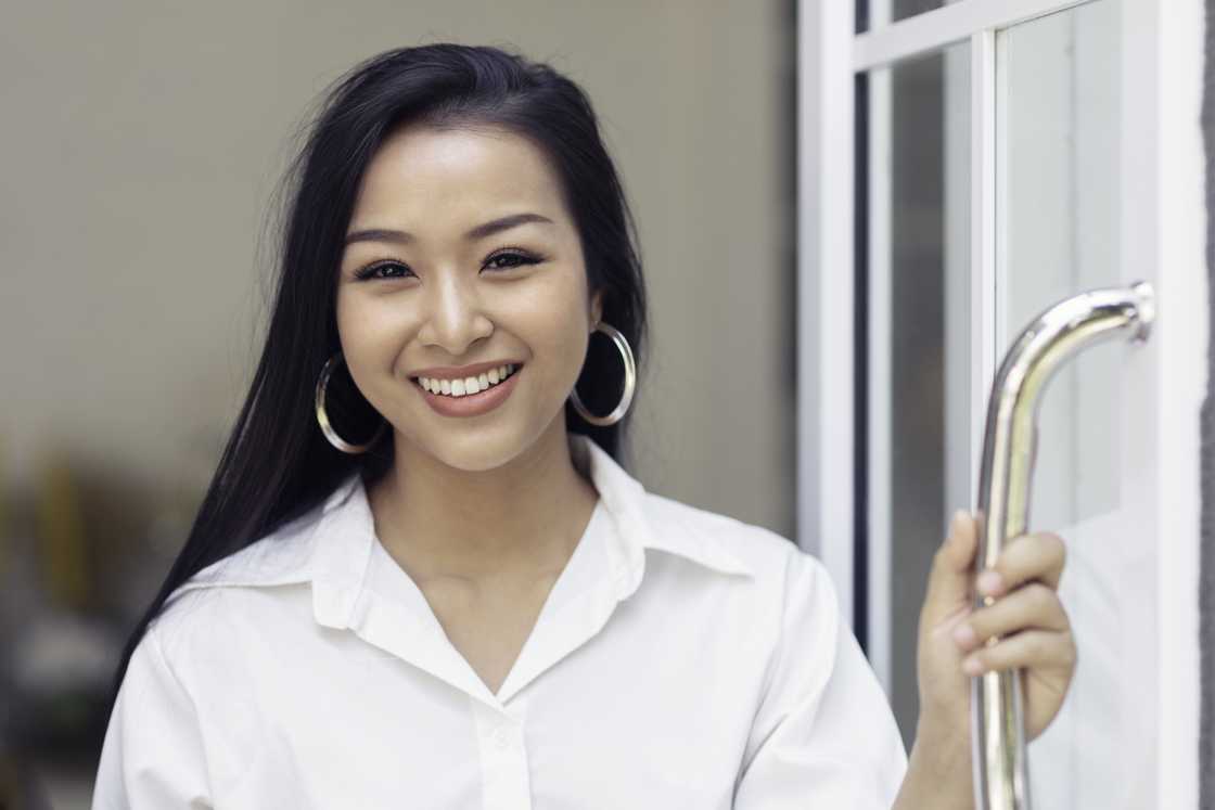 A woman holds a door open and smiles