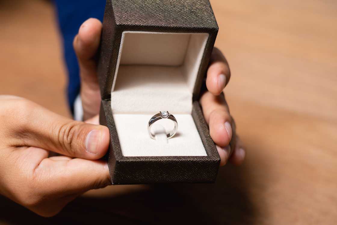 A man's hands holding a ring box with a wedding ring. A man's hands holding a ring box with a wedding ring.