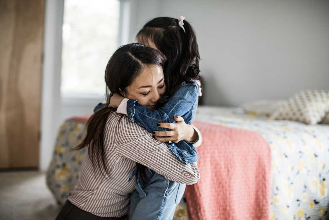 A woman and her daughter hugging with closed eyes A woman and her daughter hugging with closed eyes